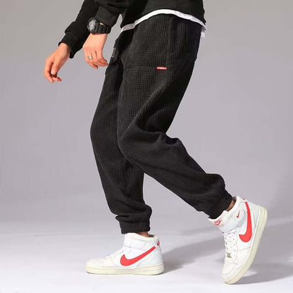 Mens Casual Pants in stylish black, paired with white and red Nike sneakers, perfect for casual outings.
