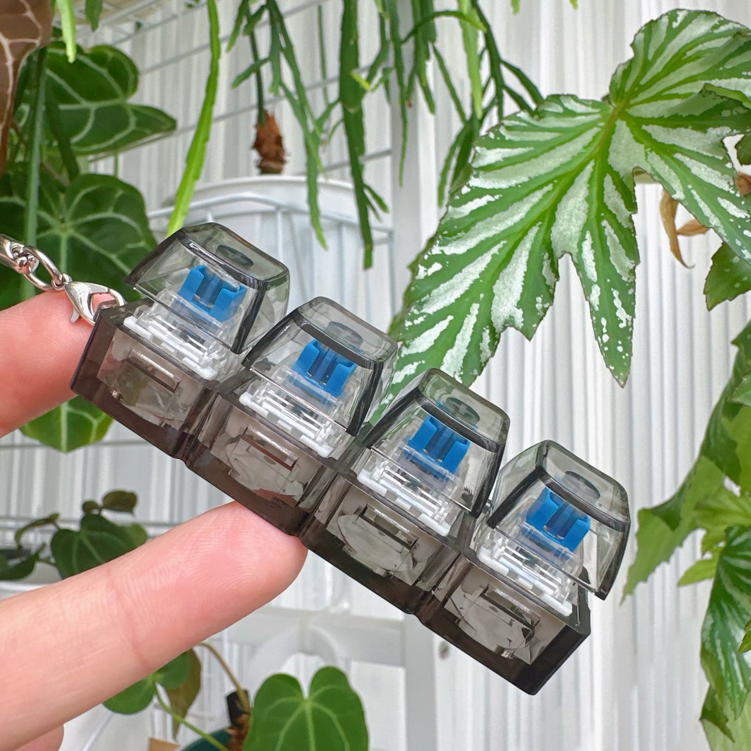Clickie Keychain in hand, showcasing its stylish design with four transparent sections and blue accents.